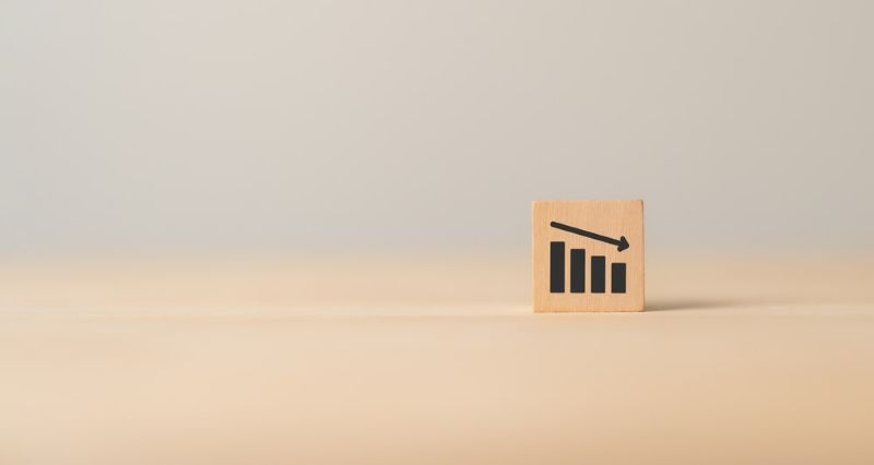 Wooden block with downward arrow and downward bar graph
