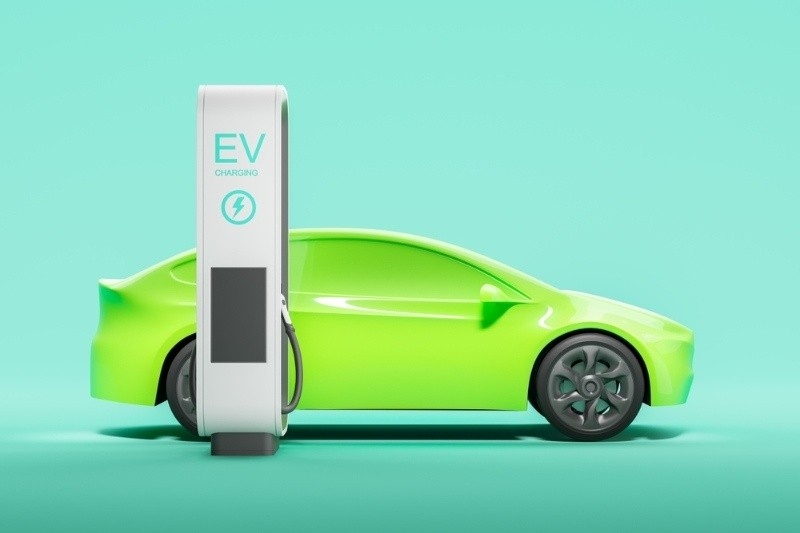Green electric car connected to an EV charging station on a minimal background.