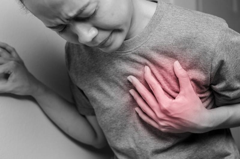 Person clutching their chest in pain with a highlighted area, indicating possible heart attack or heart-related discomfort.