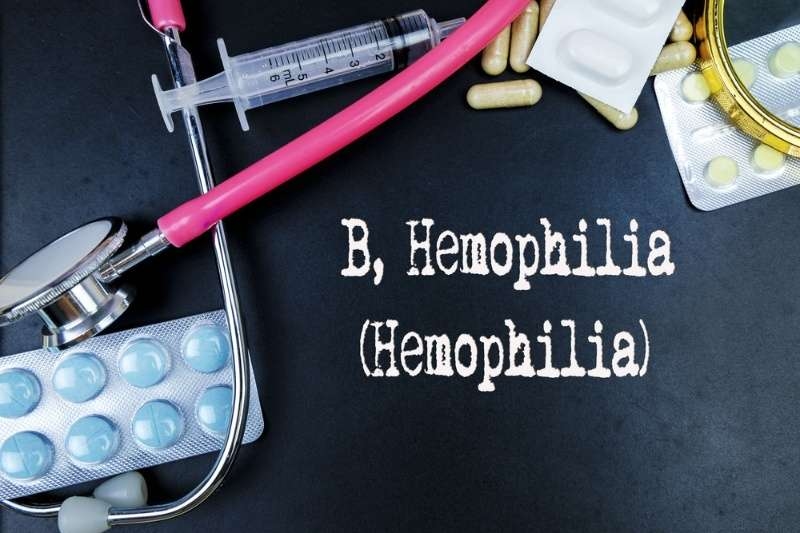 Medical concept image for hemophilia with stethoscope, syringe, pills, and text on a black background.