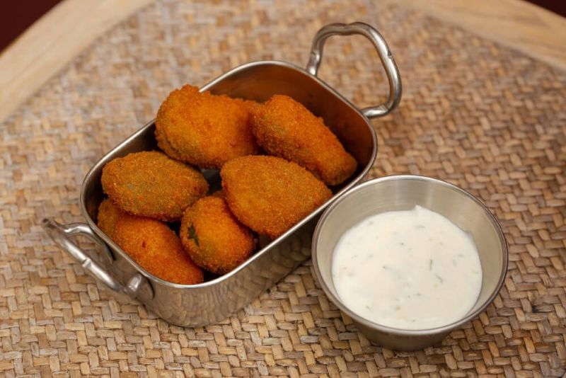 Deep fried jalapeño poppers in a steel vessel with dip
