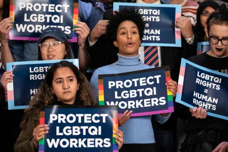 Group of people holding signs that read “Protect LGBTQI Workers” and “LGBTQI Rights = Human Rights,” advocating for equal rights.
