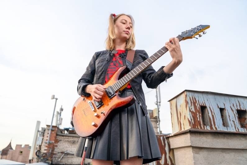 4. Female guitarist playing an electric guitar outdoors on a rooftop in an urban setting.