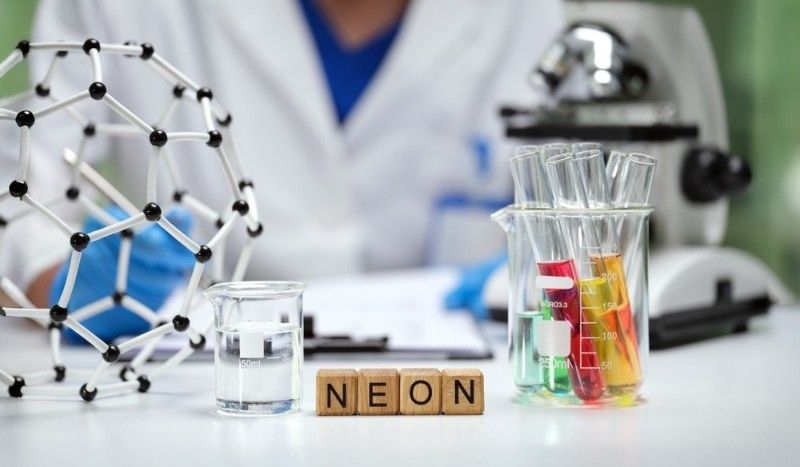 A trained scientist conducts experiments with neon gas, test tubes, and molecular models in a equipped lab