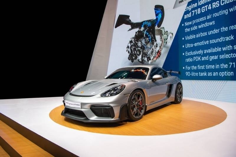 Porsche 718 sports car showcased on a presentation stage with technical display backdrop.