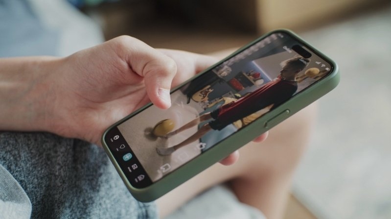 Person holding a smartphone and watching a short-form video on a social media app.