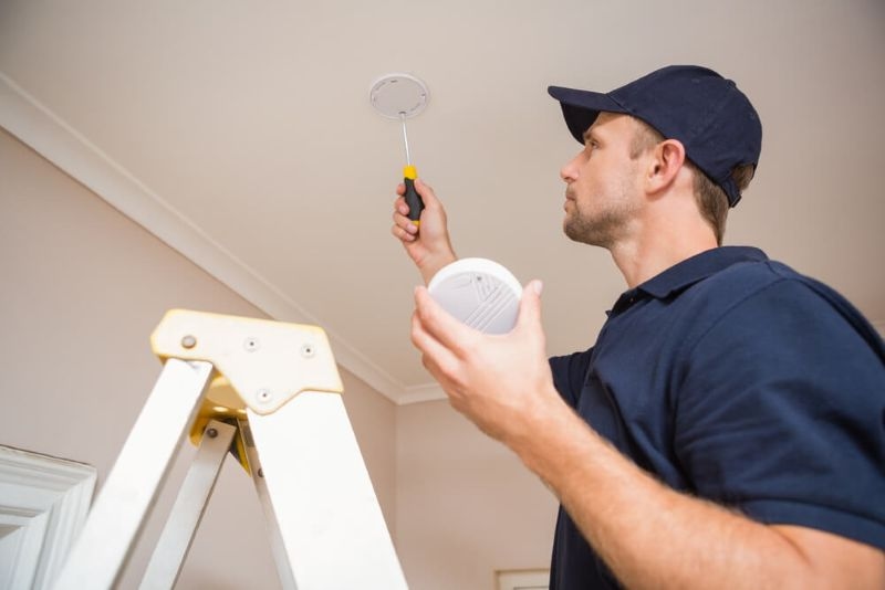 Technician installing a smoke detector for home safety