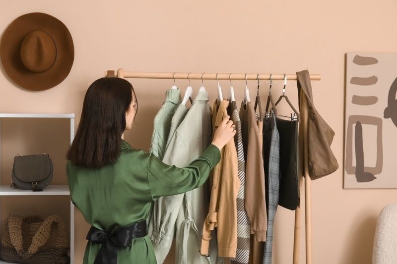 Person browsing clothes on a rack in a minimalist wardrobe setup.
