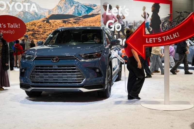 Toyota SUV displayed at an auto show with people around and a large 'Let's Talk' arrow sign pointing toward the vehicle.