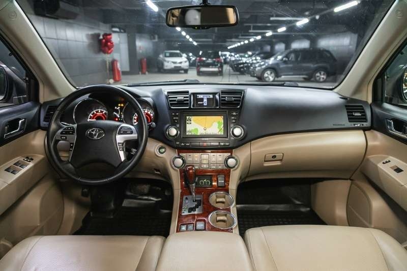 Luxury Toyota SUV interior featuring dashboard, steering wheel, touchscreen navigation, and beige leather seats.