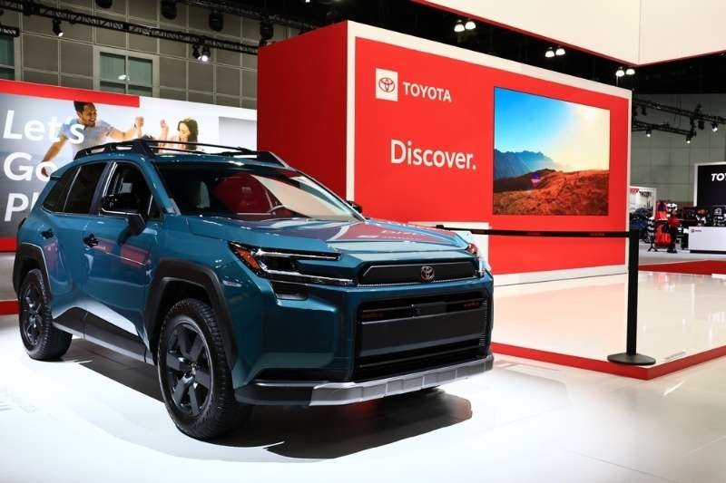 Toyota SUV displayed at an auto show booth with branding and promotional screens.