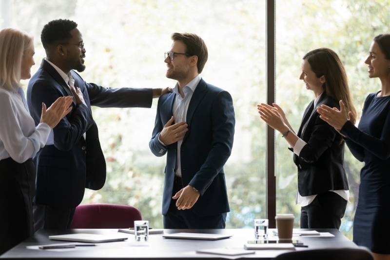 Business team applauding a colleague during a meeting, showing recognition and appreciation.