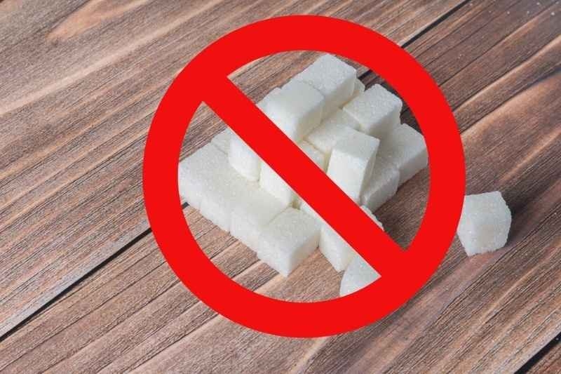 White sugar cubes displayed on a wooden surface with a red prohibition symbol over them.