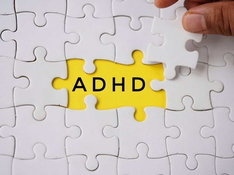 A yellow puzzle piece labeled “ADHD” surrounded by white puzzle pieces.