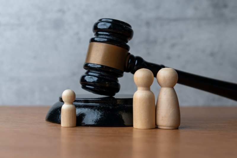 Wooden family figures positioned beside a judge’s gavel.