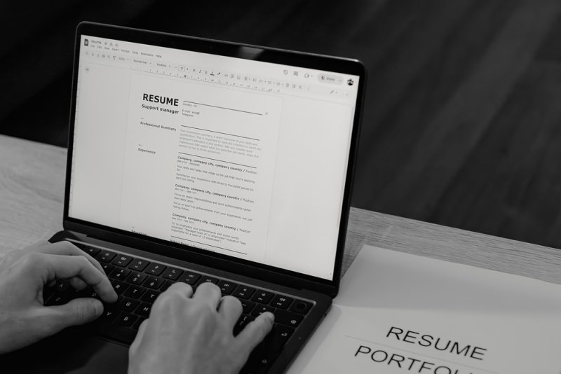 Job applicant editing a resume on a laptop to match a job description.