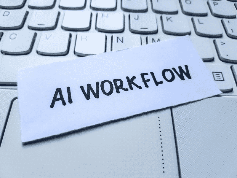 Text AI WORKFLOW on a piece of paper on top of a laptop keyboard 