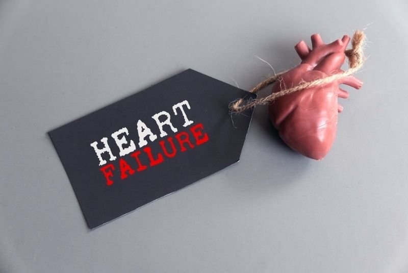 A black tag labeled “HEART FAILURE” lies beside a model of a human heart.