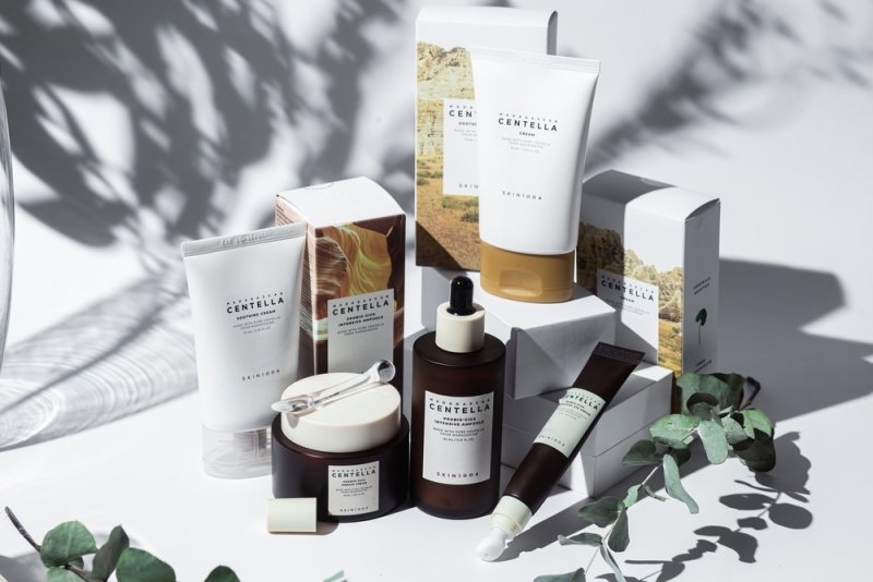 Skincare products arranged in a bright product display with packaging, jars, tubes, and decorative greenery.