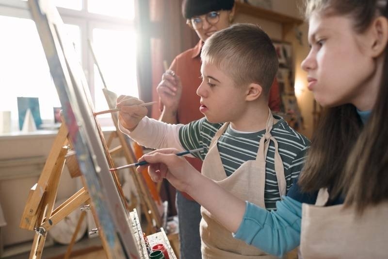 Children participating in a guided painting activity at easels in an art therapy or art class setting.