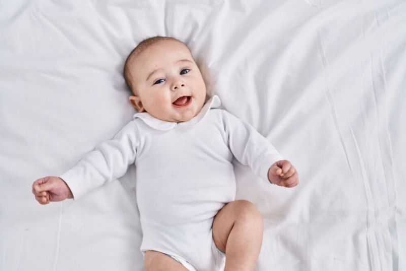 Adorable baby smiling confident lying on bed at bedroom