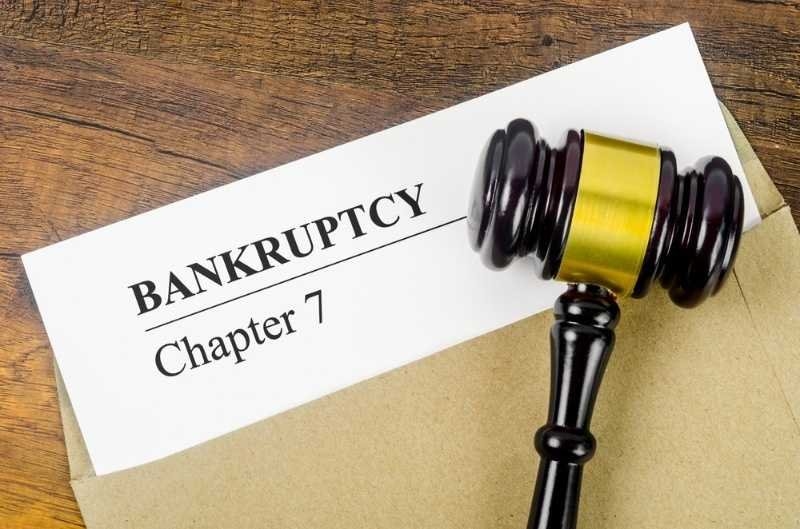 A wooden judge’s gavel rests beside a document labeled “BANKRUPTCY Chapter 7.”