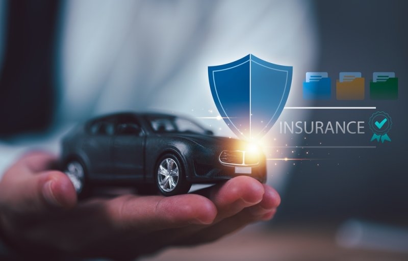Hand holding a miniature black car alongside a digital shield and verification icon.