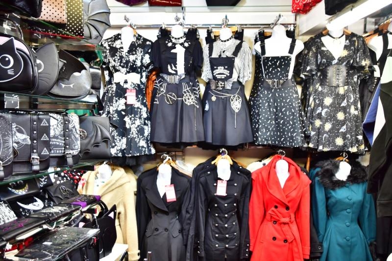 Store display featuring gothic dresses, coats, handbags, and alternative-style clothing in predominantly black and red.