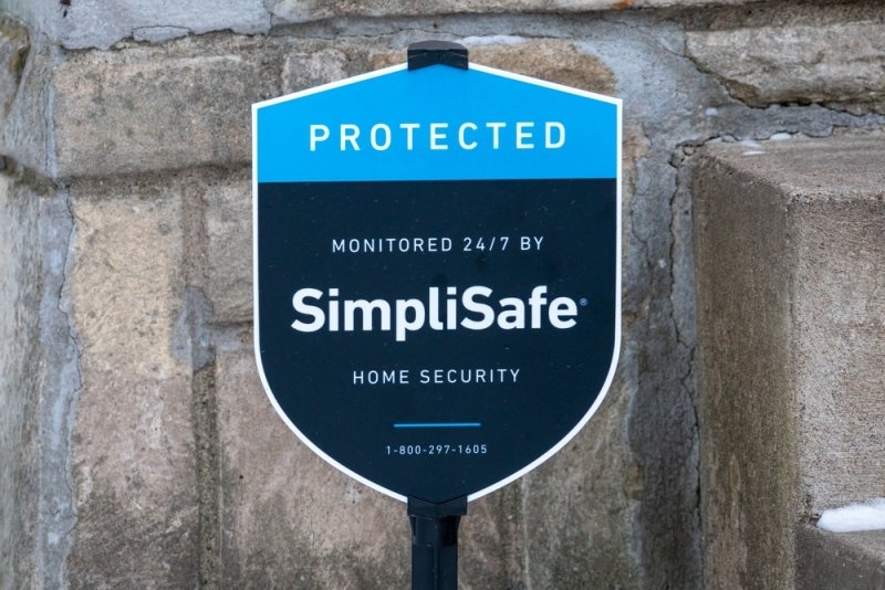 SimpliSafe home security sign showing 24/7 monitoring outside a property.