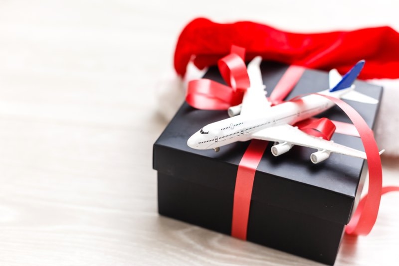 Model airplane placed on a black gift box wrapped with red ribbon.