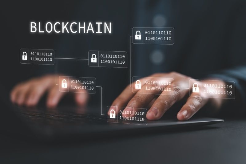 Hands typing on a laptop with blockchain network icons and digital locks overlay, representing secure data technology.