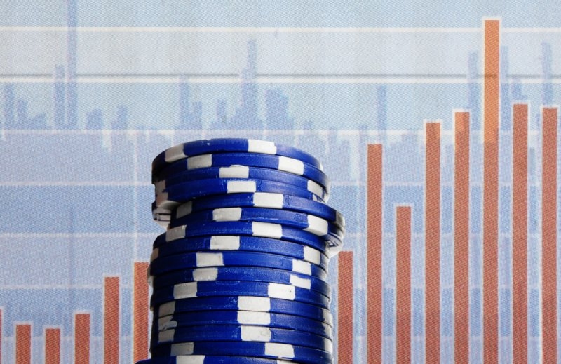Blue poker chips on stock market chart background.