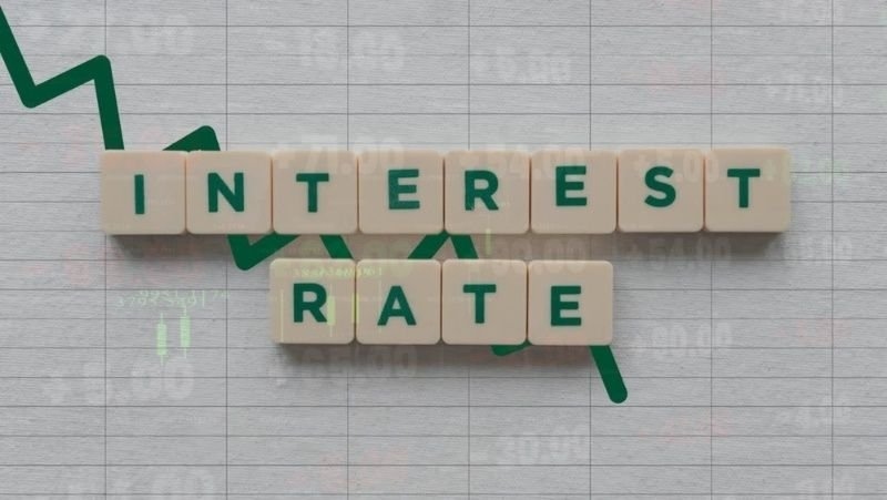 Scrabble Tiles Spelling "INTEREST RATE" Over a Downward Financial Graph, Illustrating Decreasing Borrowing Costs and Monetary Policy Shifts.