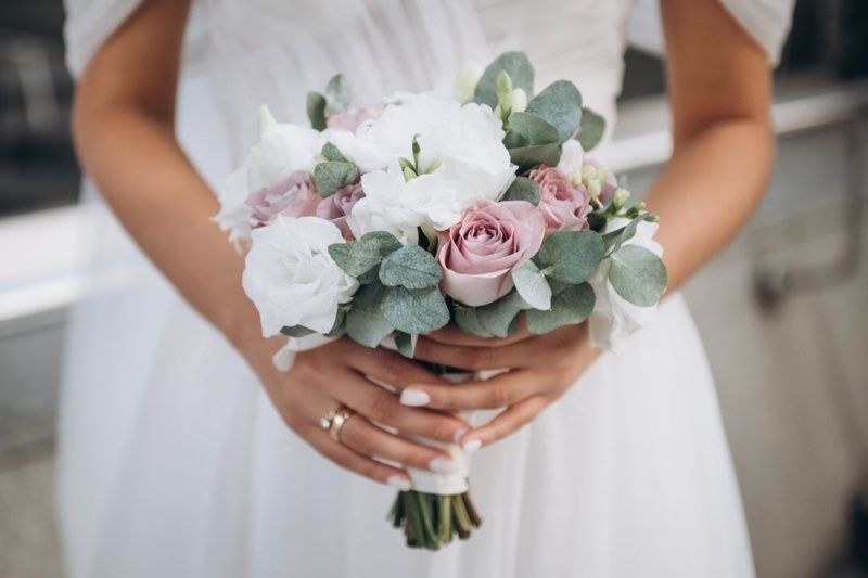 Bride holding a bouquet of white and pink flowers with eucalyptus leaves.