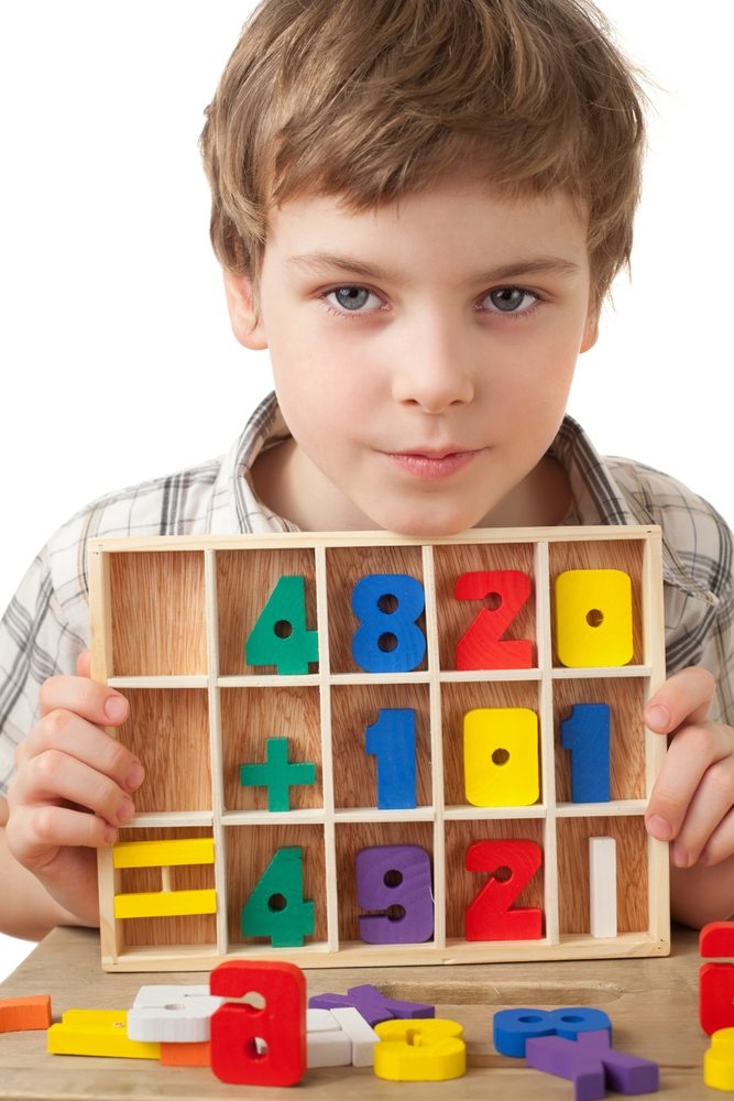 boy plays with wooden figures in form of numerals