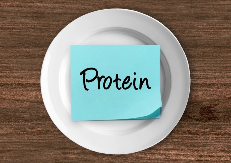 Blue note labeled “Protein” placed on a white plate over a wooden table.