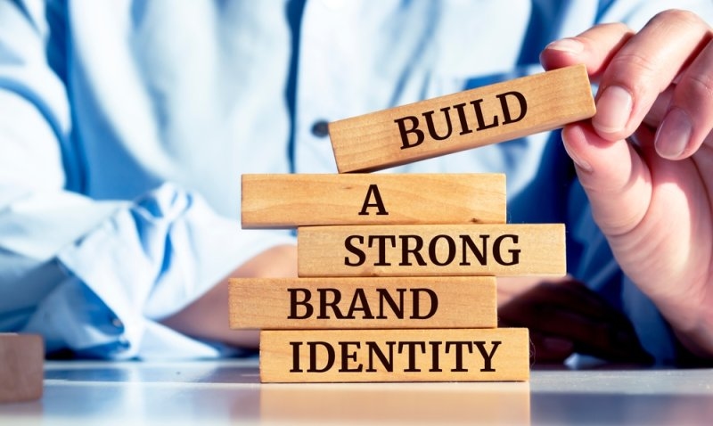Close up on businessman holding a wooden block with "Build a strong brand identity" message.