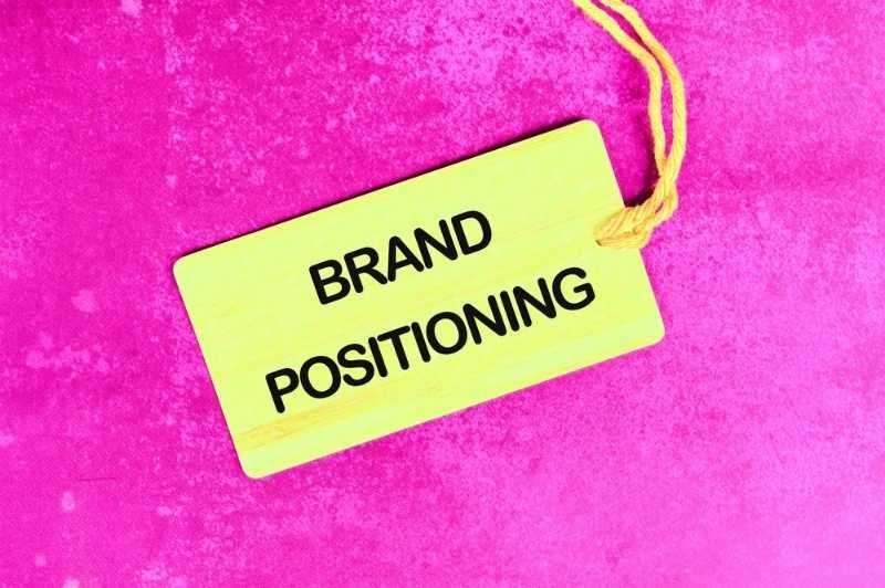 Close-up of a tag labeled "Brand Positioning" on a vibrant pink background.