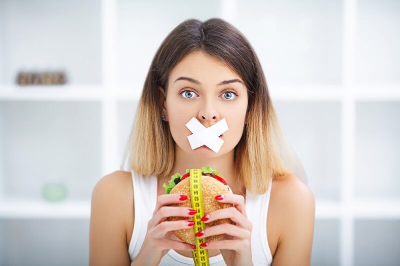 woman avoiding junk foods by tapping her mouth
