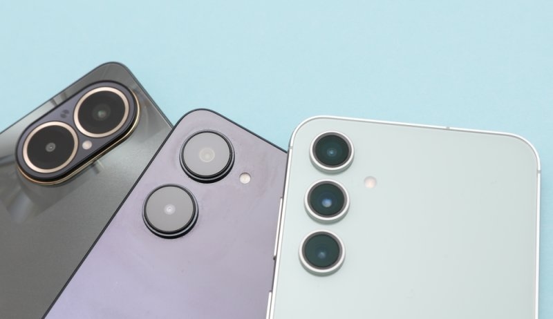 Close-up of three modern smartphones with multiple rear camera lenses arranged against a light blue background.