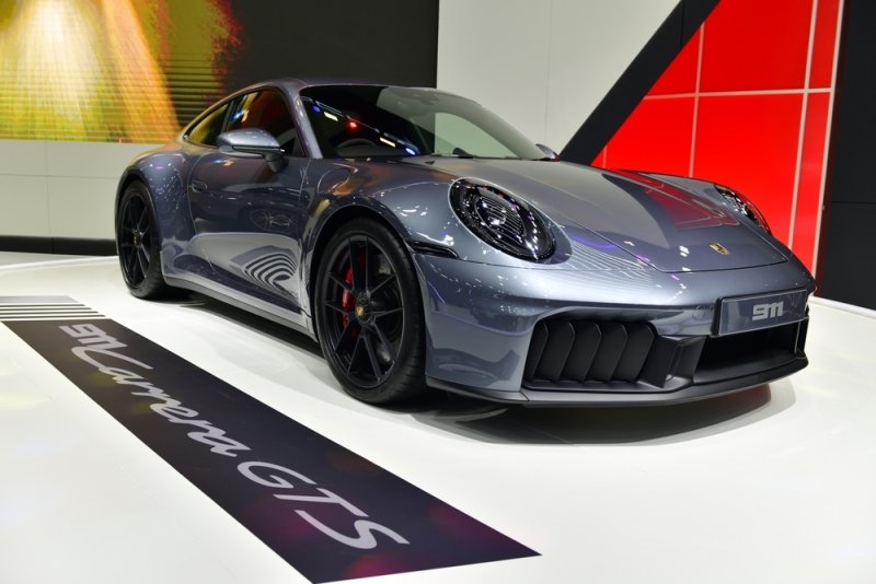 Gray Porsche sports car showcased indoors at an automotive exhibition.