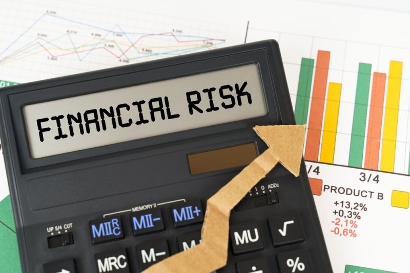 Calculator displaying “Financial Risk” alongside business charts and a downward-pointing arrow.