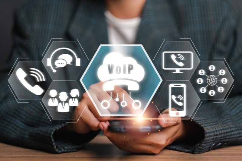 Businessperson using a smartphone with VoIP communication icons.