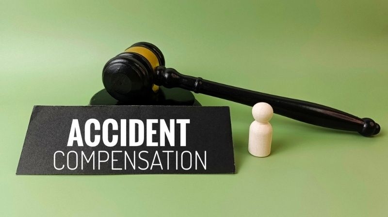Gavel and figure beside a sign reading ‘Accident Compensation,’ representing legal claims.