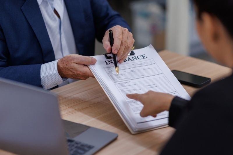  insurance agent showing place for signature on paper contract document to client. 