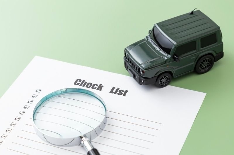 Magnifying glass placed over a checklist beside a model SUV.