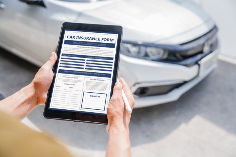 man filling up a car insurance form online on his tablet