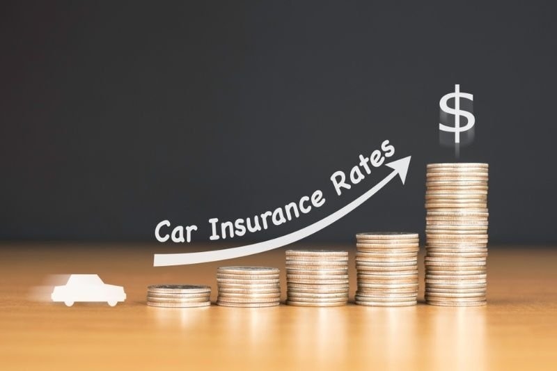 6. Stack of coins with an upward arrow labeled “Car Insurance Rates,” representing rising auto insurance premiums and pricing trends.