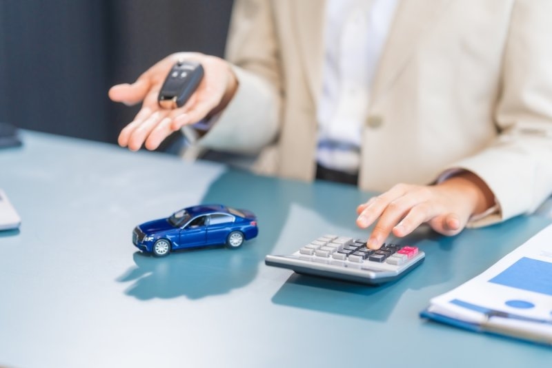 A woman with a calculator and car key in hand