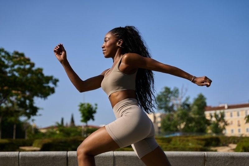 Fit black woman sprinting through a vibrant city park.